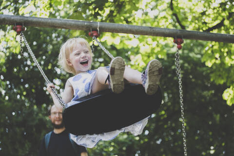 Porträt eines glücklichen kleinen Mädchens auf einer Schaukel, lizenzfreies Stockfoto