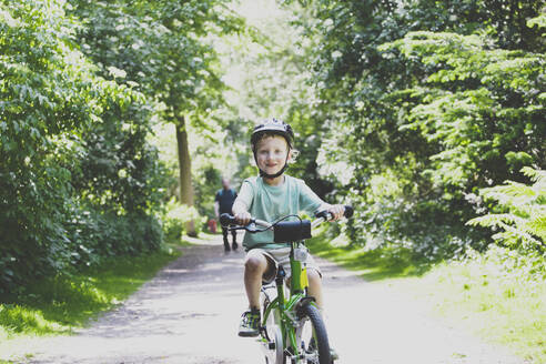 Porträt eines stolzen kleinen Jungen, der Fahrrad fahren lernt - IHF00143