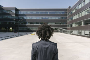 Rear view of businessman with dreadlocks standing outside office - AHSF00531