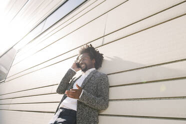 Smiling businessman talking on cell phone outside office - AHSF00549