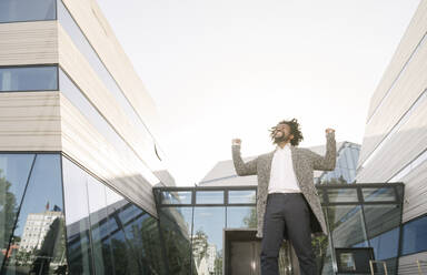 Excited businessman cheering outside office - AHSF00553