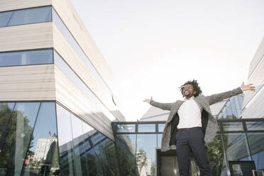 Happy businessman cheering outside office - AHSF00554