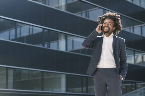 Smiling businessman talking on cell phone outside office stock photo