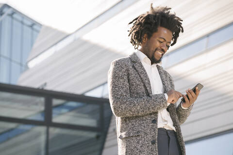 Smiling businessman using cell phone outside office stock photo