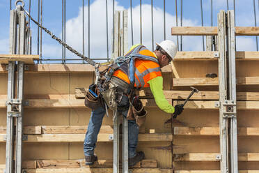 Caucasian worker hammering wood at construction site - BLEF07648