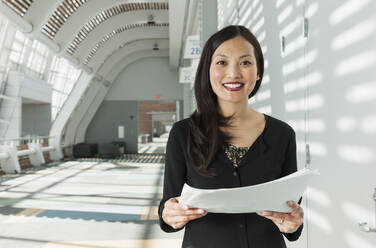 Japanese businesswoman holding papers in office - BLEF07679