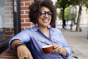 Woman having coffee on city street - BLEF07708