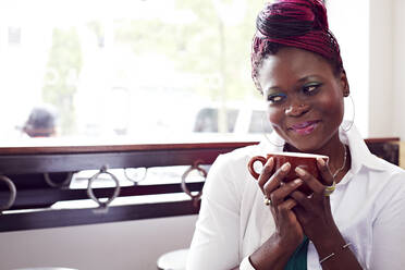 Woman drinking cup of coffee in cafe - BLEF07715