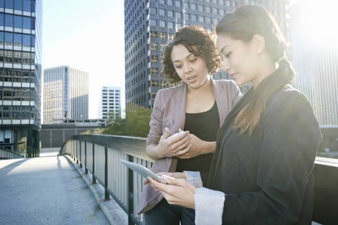 Geschäftsfrauen verwenden Tablet-Computer auf einer städtischen Himmelsbrücke - BLEF07728