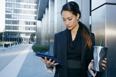 Mixed race businesswoman using tablet computer on city street - BLEF07732