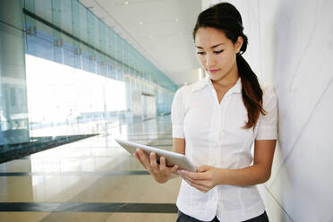 Mixed race businesswoman using tablet computer in lobby - BLEF07738