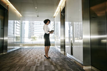 Mixed race businesswoman using tablet computer in lobby - BLEF07742