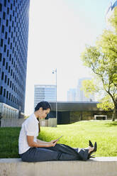 Mixed race businesswoman using tablet computer in city - BLEF07749