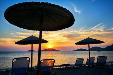 Sonnenschirme und Liegestühle am Strand bei Sonnenuntergang, Limnos, Khios, Griechenland - ISF21526