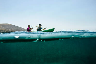 Teenage boy and mother sea kayaking, surface level side view, Limnos, Khios, Greece - ISF21531