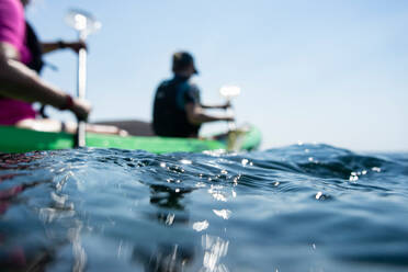 Teenage boy and mother sea kayaking, surface level shallow focus side view, Limnos, Khios, Greece - ISF21535