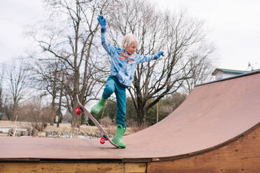 Junge auf ländlicher Skateboard-Rampe übt Skateboard-Trick - ISF21543