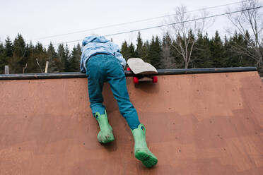 Junge klettert auf die Spitze einer Skateboard-Rampe, Rückansicht - ISF21544