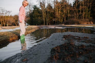 Boy ankle deep in rural puddle, portrait - ISF21556
