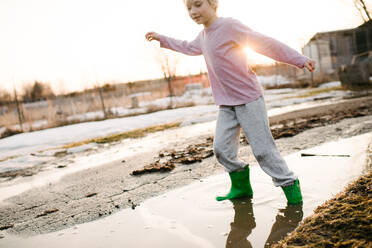 Boy playing in rural meltwater puddle - ISF21558