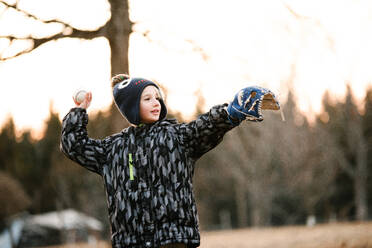 Boy preparing to throw baseball ball in rural field - ISF21560