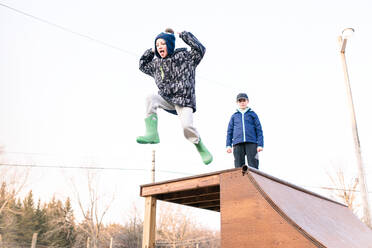 Mädchen beobachtet Bruder Sprung von der Spitze der Skateboard-Rampe - ISF21577