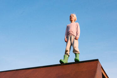 Junge, der auf einer Skateboard-Rampe vor blauem Himmel steht, Tiefblick - ISF21578