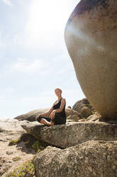 Junge Frau übt Lotus-Yoga-Pose auf Strandfelsen, Porträt, Kapstadt, Westkap, Südafrika - ISF21590