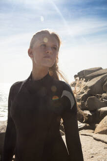 Young female surfer looking sideways on beach, Cape Town, Western Cape, South Africa - ISF21598