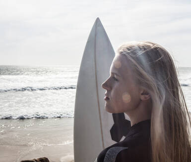 Young female surfer with surfboard gazing on beach, Cape Town, Western Cape, South Africa - ISF21640