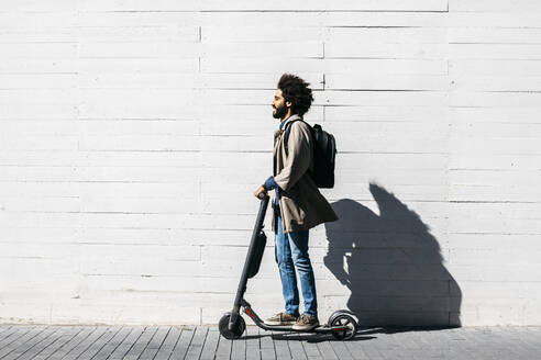 Mann mit Rucksack auf E-Scooter - JRFF03338