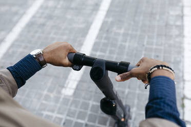 Hands of man holding handlebar of E-Scooter - JRFF03352