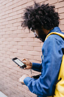 Man with backpack and E-Scooter using navigation app on his mobile phone - JRFF03370