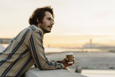 Mann mit Kaffee zum Mitnehmen beim Sonnenuntergang, Barcelona, Spanien - AFVF03326
