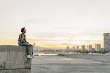 Man relaxing on a wall during sunset, Barcelona, Spain - AFVF03329