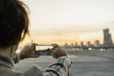Rückansicht eines Mannes beim Fotografieren während des Sonnenuntergangs, Barcelona, Spanien - AFVF03332