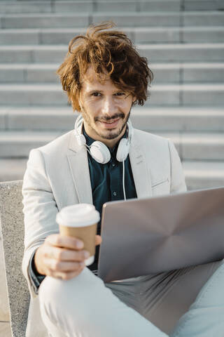 Porträt eines Geschäftsmannes mit Coffee to go und Laptop im Freien, lizenzfreies Stockfoto