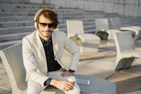 Porträt eines Geschäftsmannes mit Sonnenbrille, der mit Kopfhörern Musik hört - AFVF03390