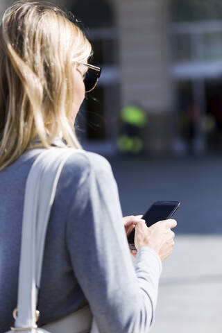 Young businesswoman texting with her mobile phone while walking stock photo