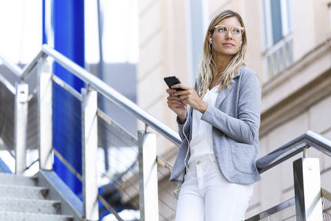 Young businesswoman texting with her mobile phone on stairs stock photo