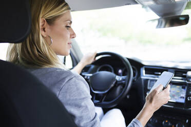 Young woman using her mobile phone in the car - JSRF00309