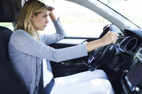 Stressed young business woman driving her car - JSRF00310