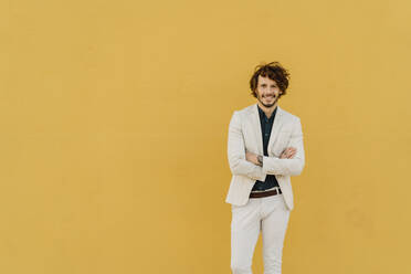 Portrait of smiling businessman in front of yellow wall - AFVF03413