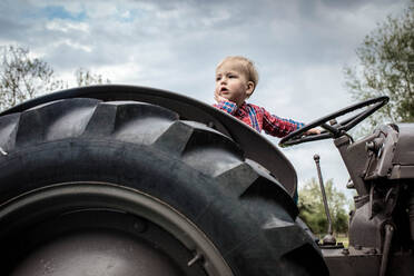 Toddler in deep thought on tractor - CUF51484