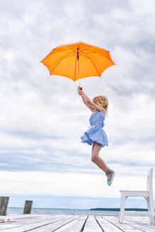 Girl being lifted off her chair by umbrella - CUF51528