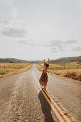 Young woman dancing on rural road, Exeter, California, USA - ISF21720