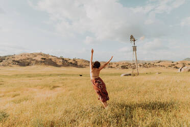 Young woman dancing in field landscape, rear view, Exeter, California, USA - ISF21722