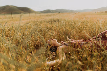 Young woman lying in field of long grass, Exeter, California, USA - ISF21727