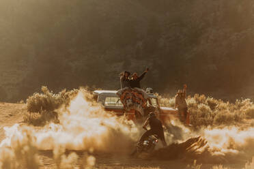 Motorbiker raising dust, friends cheering on in background, Kennedy Meadows, California, US - ISF21742