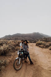 Couple relaxing on motorbike, Kennedy Meadows, California, US - ISF21773